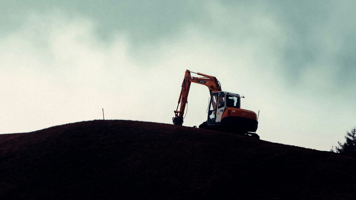 A digger sitting idle on a hilltop against an overcast sky